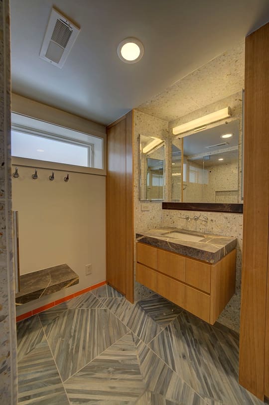 Bathroom with terrazzo-look tile walls, a floating wood vanity and a gray chevron tile floor