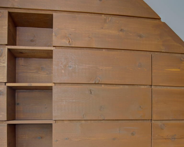 Wall of custom wood drawers and open cubbies fitted under a sloped ceiling
