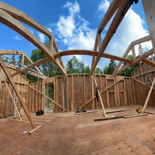 Curved timber roof trusses being framed on a house
