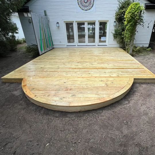 New ground-level wood deck with a curved end outside a set of patio doors