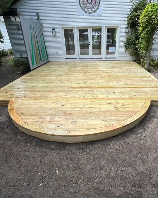 New ground-level wood deck with a curved end outside a set of patio doors
