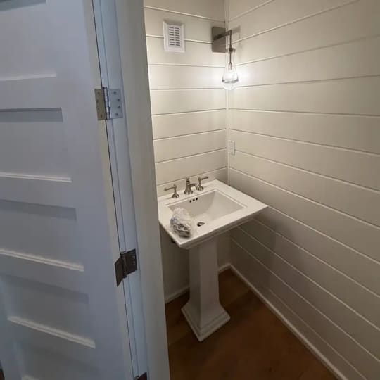 Small half bath with a pedestal sink and white shiplap walls