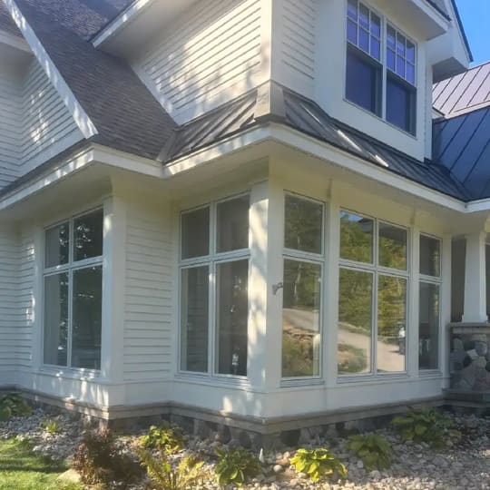Multi-level home with white siding, a shingle roof and metal roofs over the bump-outs