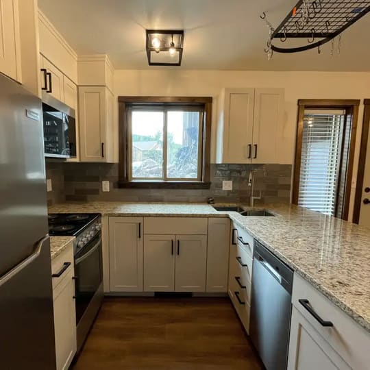 Kitchen peninsula with white cabinets below a wood-trimmed window