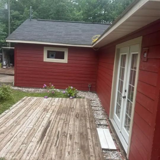 Back deck of a red house with white French doors