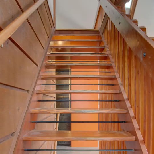Open-riser floating stairs with orange-stained treads seen from above