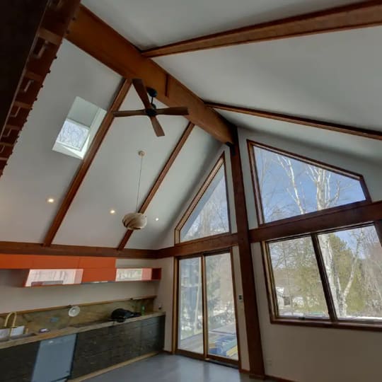 Vaulted wood ceiling with exposed beams above orange-stained cabinets