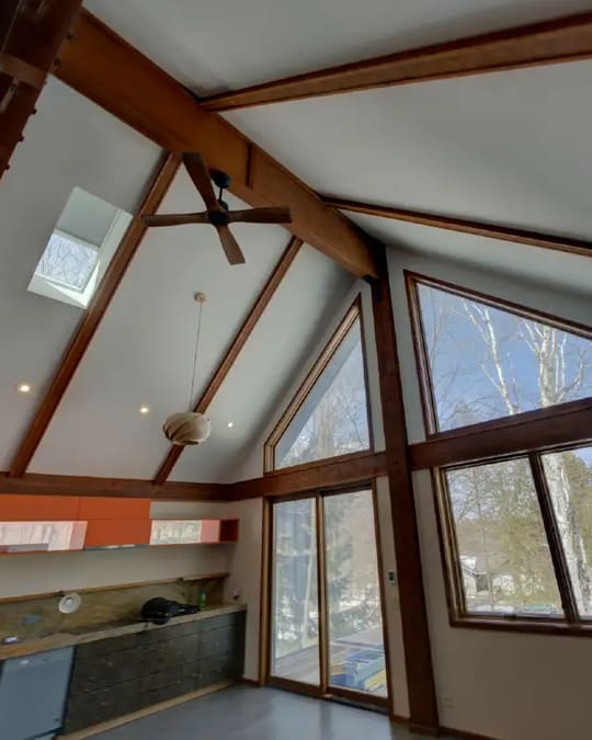 Remodeled room with a vaulted wood ceiling, exposed beams and orange-stained cabinets