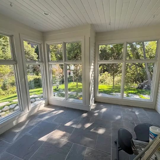 Sun porch with floor-to-ceiling windows on three sides and a tile floor
