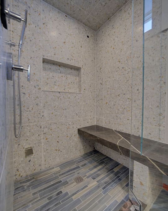 Walk-in tiled shower with a floating bench and a plank-tile floor