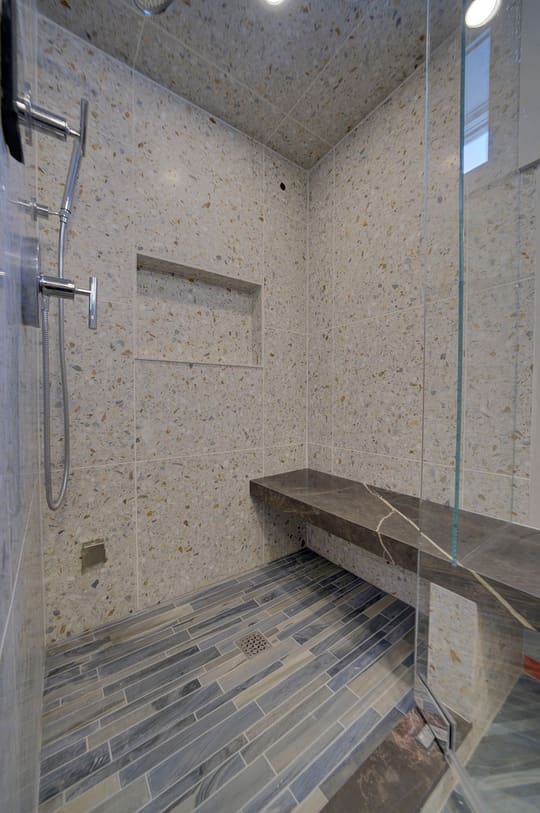 Walk-in tiled shower with a floating bench and a plank-tile floor